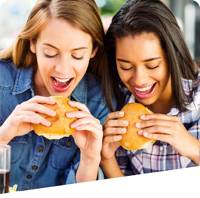 Two young women enjoying sandwiches made with freshly baked bread.